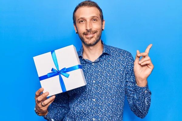 Jovem Homem Bonito Segurando Presente Sorrindo Feliz Apontando Com Mão — Fotografia de Stock