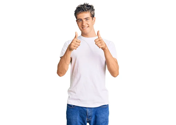 年轻英俊的男子穿着随意的白衬衫 成功的标志着他用手做了一个积极的手势 竖起大拇指 微笑着 快乐地 快乐的表达和胜利的姿态 — 图库照片