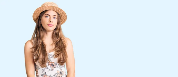 夏の帽子をかぶっている美しい白人の若い女性は 顔に深刻な表情でリラックスしています カメラを見ているだけで — ストック写真
