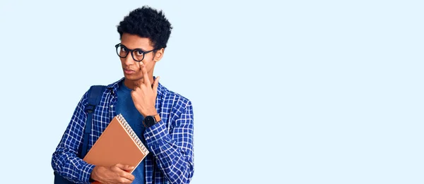 Joven Afroamericano Con Mochila Estudiantil Sosteniendo Libro Apuntando Ojo Observándote —  Fotos de Stock