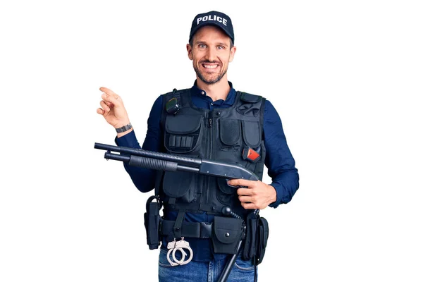若いですハンサムな男身に着けています警察制服保持ショットガン笑顔幸せなポインティングとともに手と指へ側 — ストック写真