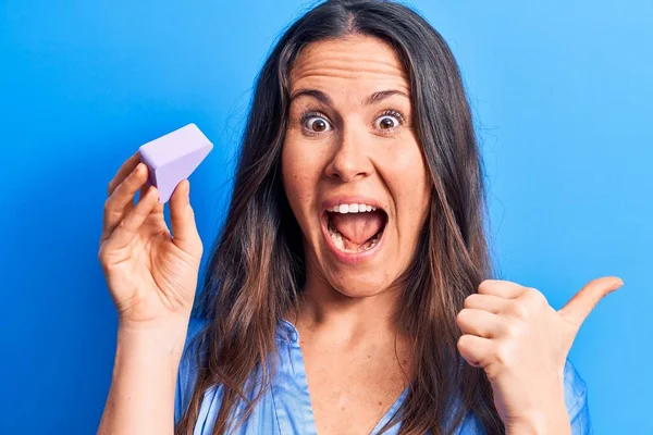 Joven Hermosa Morena Aplicando Maquillaje Usando Esponja Sobre Fondo Azul —  Fotos de Stock