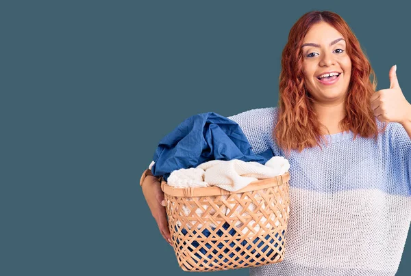 Mujer Latina Joven Sosteniendo Cesta Ropa Sonriendo Feliz Positivo Pulgar —  Fotos de Stock