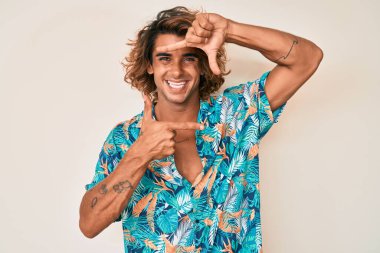 Yazlık tişört giyen, gülümseyen, elleri ve parmakları gülen yüzlü genç bir İspanyol. yaratıcılık ve fotoğrafçılık kavramı. 