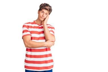 Gündelik kıyafetler giyen yakışıklı genç adam kollarını kavuşturarak depresyondan sıkılmış ve yorgun görünüyor.. 