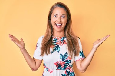 Orta yaşlı İspanyol kadın gündelik çiçekli elbiseler giyerek zaferi mutlu bir gülümsemeyle kutluyor ve ellerini kaldırarak kazanan yüz ifadesi sergiliyor. 