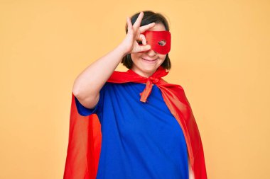 Down sendromlu esmer kadın, süper kahraman kostümü giyiyor, gülümsüyor. 