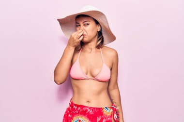 Bikini giyen ve şapka takan genç bir kadın pis ve iğrenç bir koku alıyor. Nefesini burnunda tutuyor. Kötü kokuyor. 