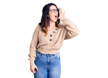 Güzel, genç, esmer, sıradan kıyafetler ve gözlük takan bir kadın el ve ağızla bağırarak ve yüksek sesle bağırıyor. iletişim konsepti. 