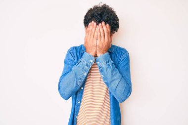 Kıvırcık saçlı ve ayı gibi giyinen, üzgün yüzlü, elleri ağlarken yüzünü kapatan yakışıklı bir genç. depresyon kavramı. 