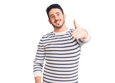 Gündelik kıyafetler giyen genç İspanyol adam dostça bir selamlama ve hoş geldin hediyesi olarak el sıkışmayı sunuyor. başarılı iş. 