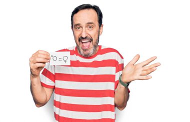 Orta yaşlı bir adam, kadın ve erkek eşitliği için kağıt tutarak başarıyı mutlu bir gülümsemeyle ve kazanan ifadeyle el kaldırarak kutluyor.