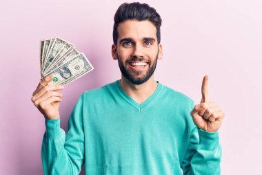 Elinde bir tomar parayla gülümseyen sakallı yakışıklı bir genç adam ya da mutlu bir yüzle işaret eden bir soru, bir numara. 