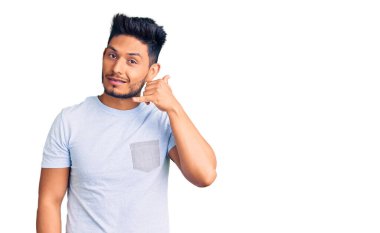 Yakışıklı Latin Amerikalı gündelik giysiler içinde gülümseyen el ve parmaklarıyla telefonla konuşan genç adam. iletişim kavramları. 