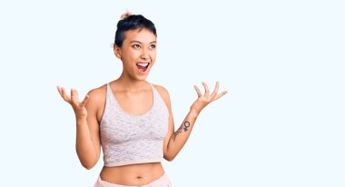 Spor kıyafetleri giyen genç bir kadın kızgın ve deli gibi bağırıyor ve agresif bir ifade ve kollarla bağırıyor. hüsran kavramı. 