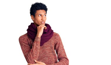 Genç Afro-Amerikan bir adam günlük kışlık süveter ve elleri çenesinde fular giyiyor. Soru sormayı düşünüyor. Düşünceli bir ifade. Gülümseyen ve düşünceli bir yüz. şüphe kavramı. 