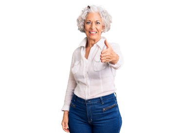 Kıdemli, gri saçlı, sıradan kıyafetler giyen, dostça gülümseyen, selamlaşmak için el sıkışan bir kadın. başarılı iş. 