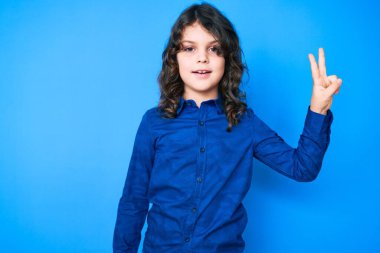 Uzun saçlı, sıradan kıyafetler giyen, gülümseyen, kameraya göz kırpan, zafer işareti yapan tatlı İspanyol çocuk. İki numara.. 