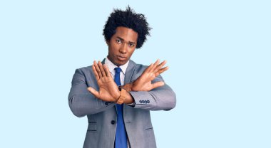 Afro saçlı, iş ceketi giyen yakışıklı Afro-Amerikalı adam. Reddedilmiş yüz ifadesi. Kollarını kavuşturmuş, avuç içleri negatif işareti yapıyor. 