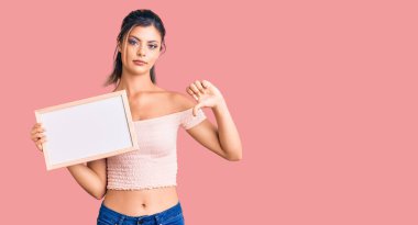 Genç, güzel bir kadın elinde kızgın yüzüyle beyaz bir karatahta tutuyor. Negatif işaretler baş parmakları aşağıda, reddedilme konsepti ise... 