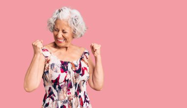 Başarı için heyecanlanan, kolları havada, gözleri kapalı, günlük giysiler giyen yaşlı, gri saçlı kadın zaferi kutluyor. Kazanan konsept. 