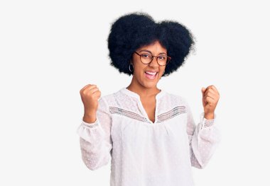 Genç Afrikalı Amerikalı kız gündelik giysiler içinde gururla bağırıyor, zaferi kutluyor ve kollarını kaldırarak çok heyecanlanıyor. 