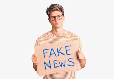 Elinde sahte haber afişi tutan yakışıklı genç adam. Düşünme tarzı ve ayık yüz ifadesi. Kendine güveni tam. 