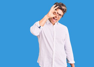 İş kıyafetleri ve gözlük takan genç yakışıklı adam el hareketleriyle gülümsüyor ve mutlu yüzüyle parmaklarının arasından bakıyor.. 