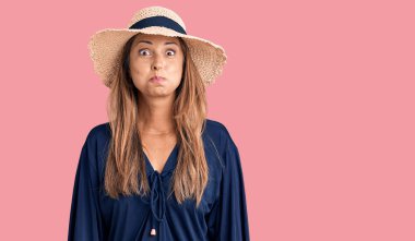 Orta yaşlı, şapkalı, komik yüzlü, yanak şişiren İspanyol bir kadın. Havayla şişmiş ağız, çılgın bir ifade.. 