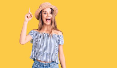 Şapka ve tişört giyen genç ve güzel bir kız başarılı bir fikri işaret ediyor. Heyecanlı ve mutlu. Bir numara.. 