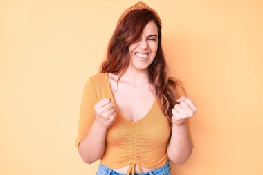 Başarı için heyecanlı, kolları havada, gözleri kapalı, sıradan kıyafetler giyen genç ve güzel bir kadın zaferi kutlarken gülümsüyor. Kazanan konsept. 