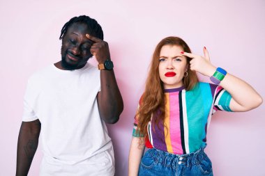 Sıradan kıyafetler giyen, alnındaki sivilceden mutsuz olduğunu gösteren ırklar arası bir çift. Siyah başlıklı çirkin bir enfeksiyon. sivilce ve deri problemi 