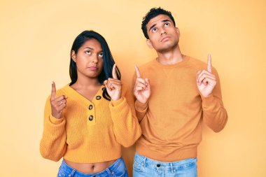 Güzel Latin genç çift, günlük kıyafetlerini giyip üzgün ve üzgün görünüyorlar, parmaklarıyla yön gösteriyorlar, mutsuz ve depresifler.. 