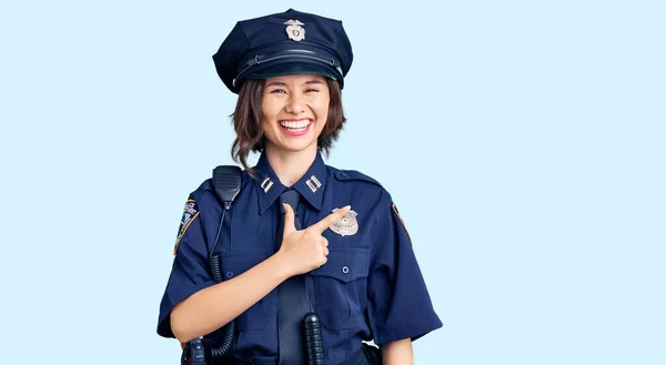 Young beautiful girl wearing police uniform cheerful with a smile of face pointing with hand and finger up to the side with happy and natural expression on face