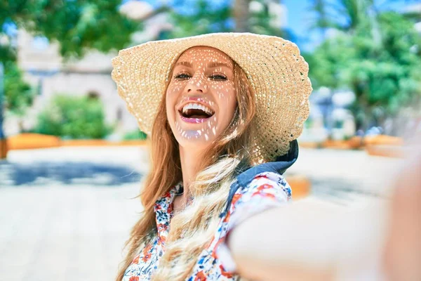 夏の帽子を身に着けて休暇中の若い美しいブロンドの女性は幸せな笑顔 街中のカメラで自撮りをする笑顔で立ち上がる — ストック写真