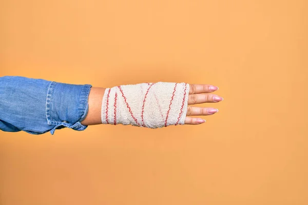 受伤的高加索年轻女子的手 用绷带包扎 用手指在孤立的黄色背景上做4号动作 — 图库照片