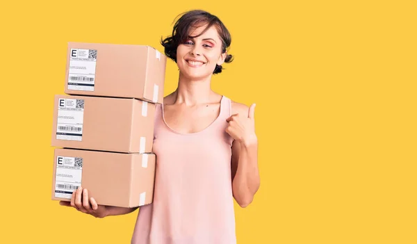 Beautiful Young Woman Short Hair Holding Delivery Packages Pointing Finger — Stock Photo, Image