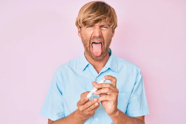 Joven Hombre Rubio Usando Glucómetro Sacando Lengua Feliz Con Expresión —  Fotos de Stock