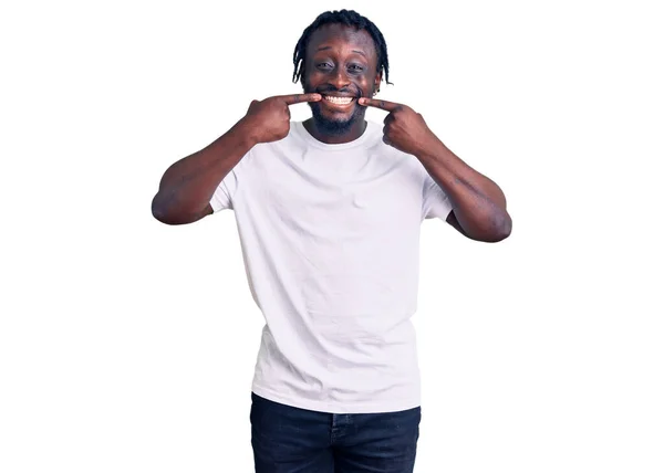 カジュアルな白いTシャツを着た若いアフリカ系アメリカ人の男性は 明るい表情と指の歯と口で指して笑っています 歯の健康の概念 — ストック写真