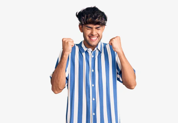 腕を上げて成功に興奮したカジュアルな服を着た若いヒスパニック系の男が育ち 目は勝利笑顔を祝う閉鎖しました 勝者のコンセプト — ストック写真
