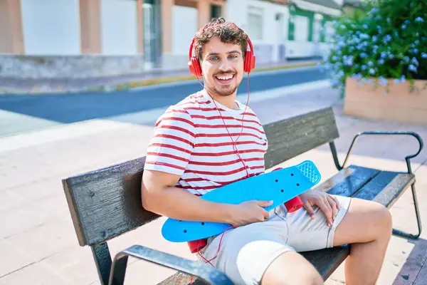 Giovane Skater Caucasico Uomo Sorridente Felice Seduto Sulla Panchina Ascoltare — Foto Stock