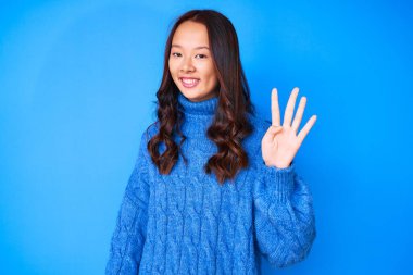 Genç, güzel, Çinli bir kız, günlük kışlık süveter giyiyor ve parmaklarıyla dört numarayı gösterip gülümsüyor. Kendinden emin ve mutlu.. 