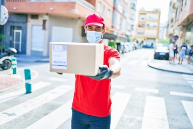 Genç teslimatçı üniforma ve koronavirüs koruma maskesi takıyor..