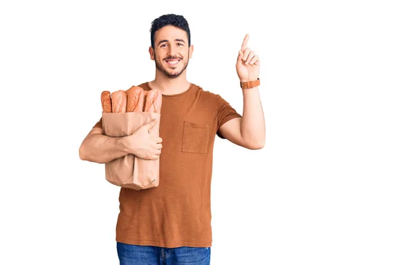 Young Hispanic Man Holding Paper Bag Bread Surprised Idea Question — Stock Photo, Image