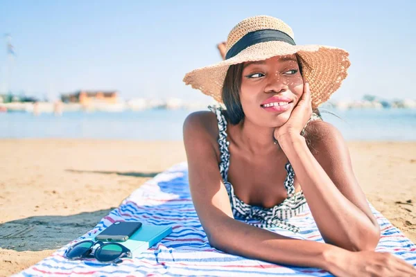若いアフリカ系アメリカ人の女性の休暇の笑顔幸せなビーチでタオルの上に横たわる — ストック写真