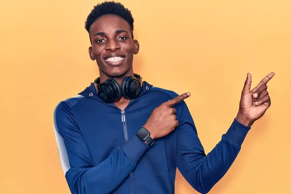 Młody Afroamerykanin Odzieży Sportowej Słuchawkach Uśmiechnięty Patrzący Kamerę Dwiema Rękami — Zdjęcie stockowe