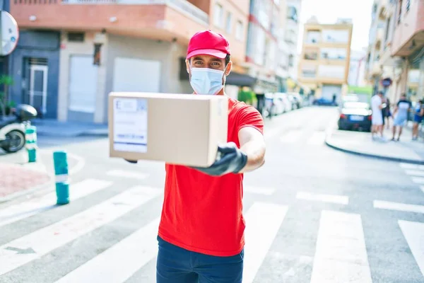 Genç teslimatçı üniforma ve koronavirüs koruma maskesi takıyor..