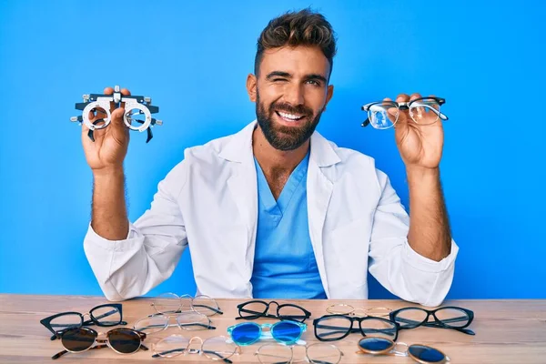 Joven Hombre Hispano Con Gafas Optometría Sentado Mesa Guiñando Ojo — Foto de Stock