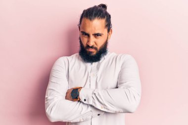 Gündelik kıyafetler giyen, kuşkucu ve gergin genç bir Arap. Yüzünde çapraz kollu tasvip etmeyen bir ifade. negatif kişi. 