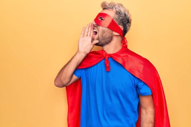 Sarı arka planda maskeli ve pelerinli yakışıklı sarışın adam el ele tutuşarak bağırıyor ve çığlık atıyordu. İletişim konsepti.